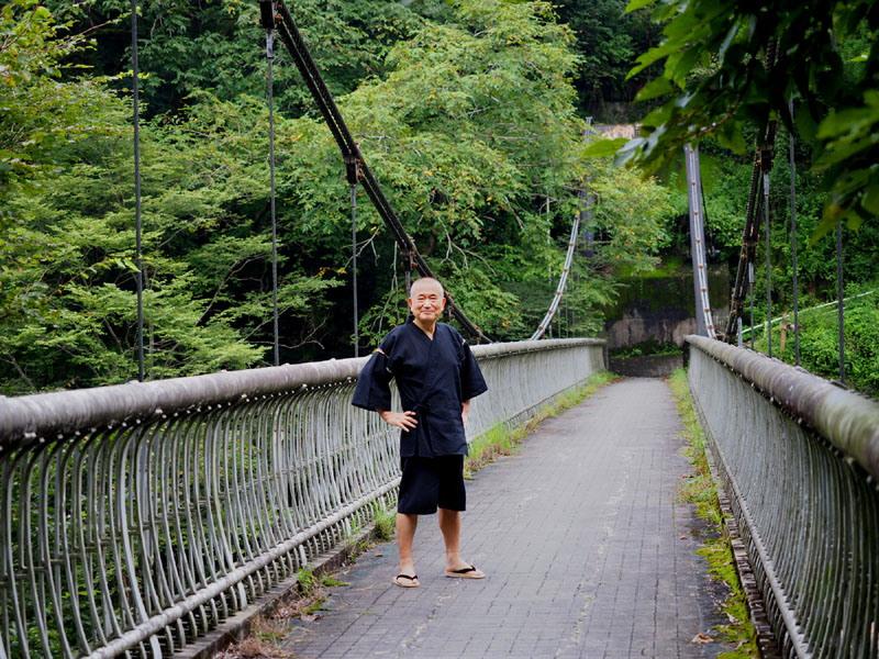 多摩川の御嶽渓谷に架かる鋼鉄製吊り橋の神路橋（かみじばし）と甚平姿の和田爺