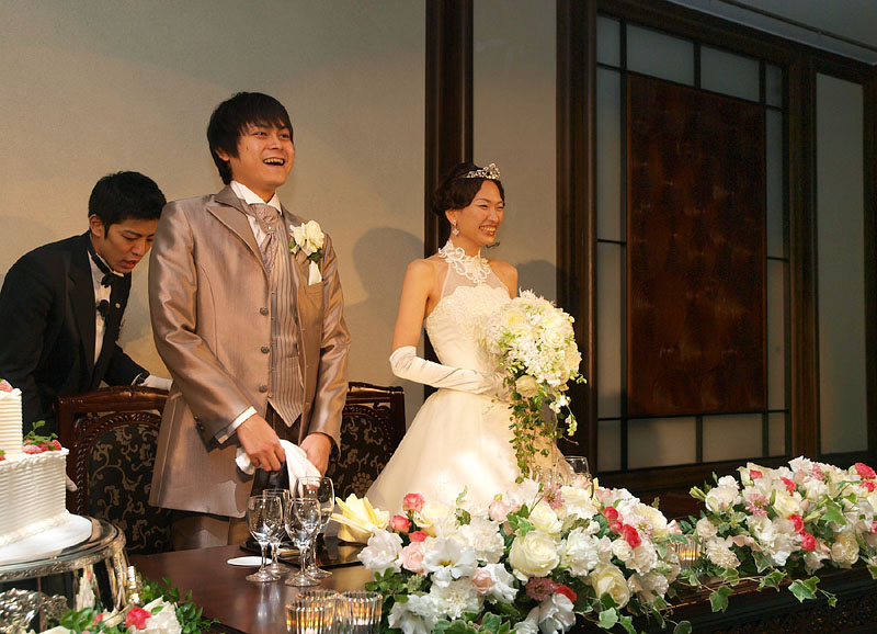 清楚な花で飾られたメインテーブルに着く二人