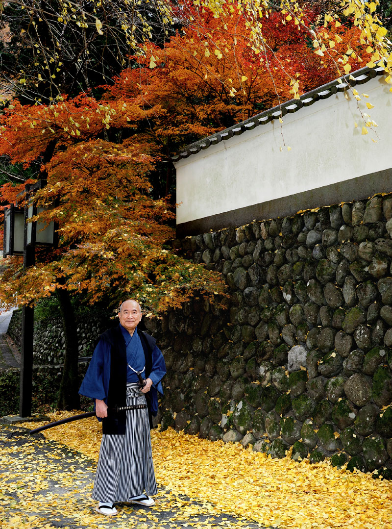 白壁と紅葉を背景に侍爺を演じる