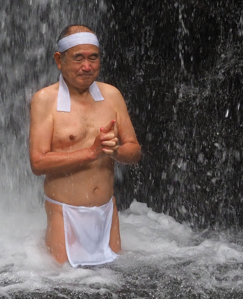 本流を背に手印を結んで滝行する和田爺