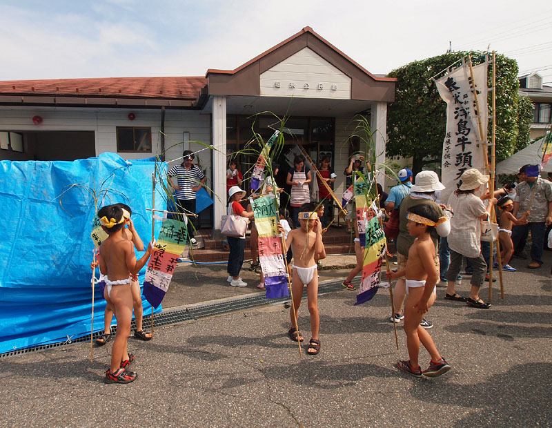 小さな五色の紙幟を持つ低学年児たち