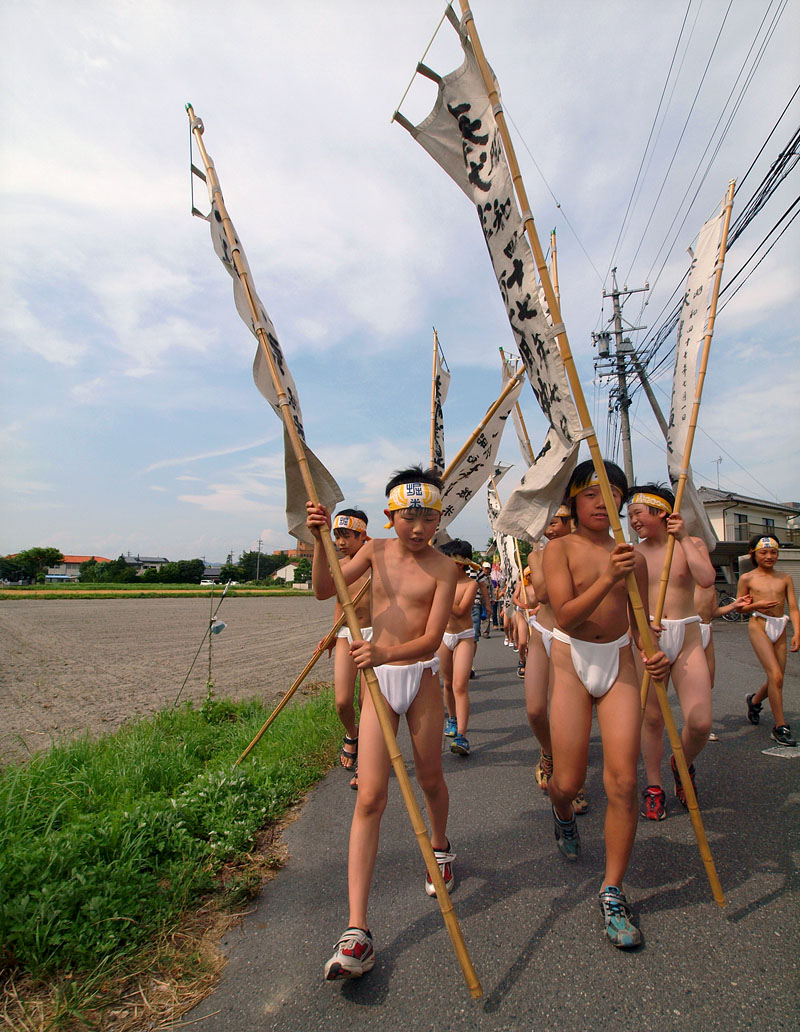 畑のそばを行く裸の行列