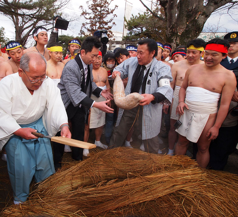 つつこ餅を背広姿の清野委員長に渡す