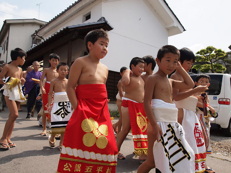 白壁の土蔵の前を下る中組たち