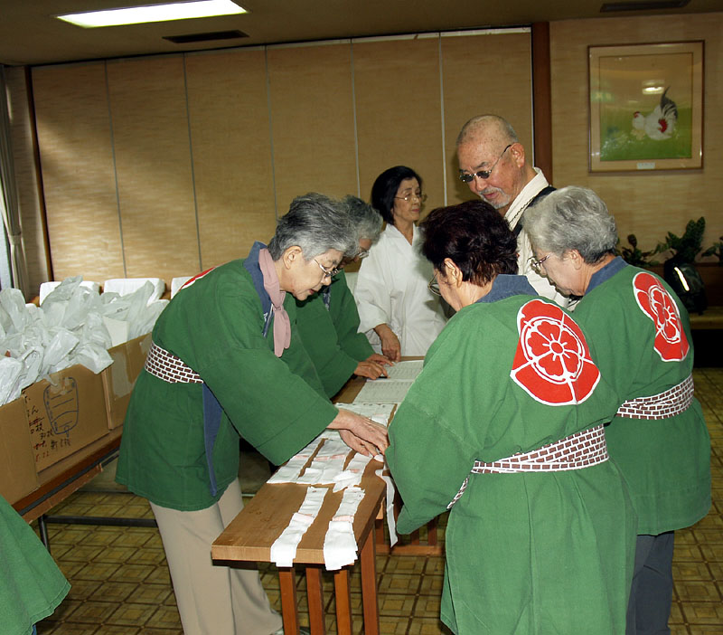 担ぎ手の予約名簿をチェックして祭装束を交付する受付係