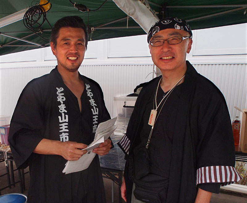 とやま山王市運営委員会実行委員長の石井隆信さん(右)と運営管理本部統括責任者の桐井康之さん/本部テント
