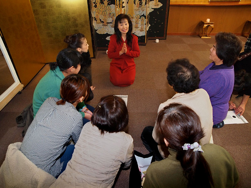 住職の奥様の説明に耳を傾ける女性参加者たち 14:38