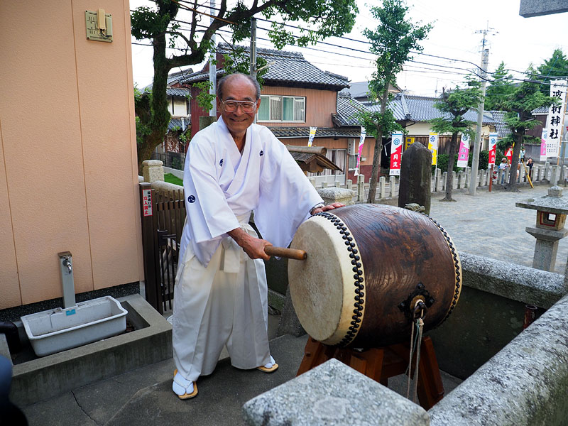 白装束の氏子が打ち鳴らす宮入り太鼓 / 波折神社社務所
