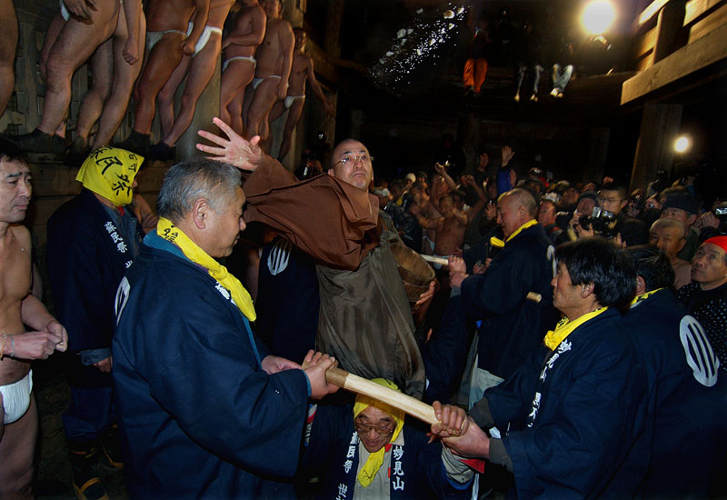護摩台で曼荼羅米と十二支の形に作った餅を撒く僧侶