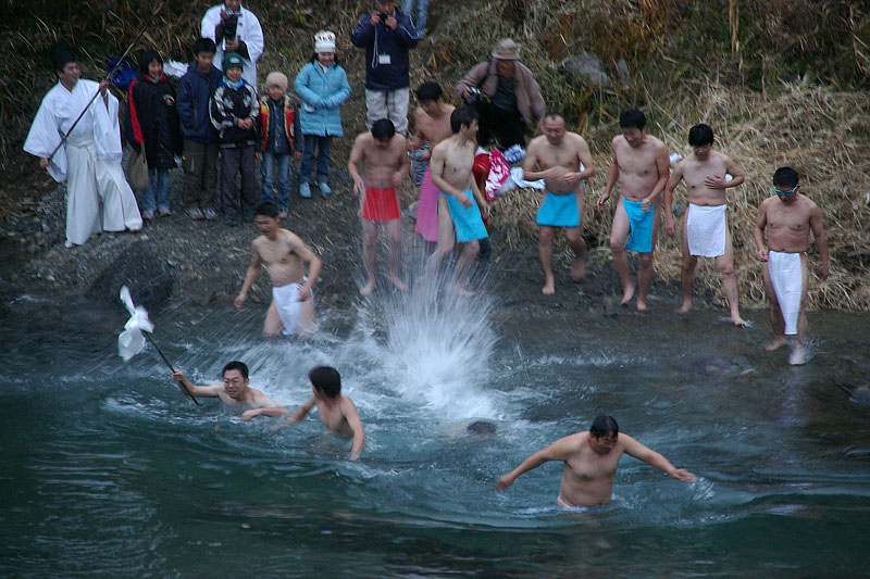 冷たい清流に飛び込む神職と氏子たち