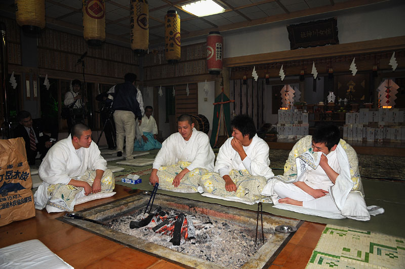 囲炉裏の炭火で暖を取る4人の行修者たち