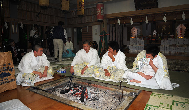 囲炉裏の炭火で暖を取る４人の行修者たち