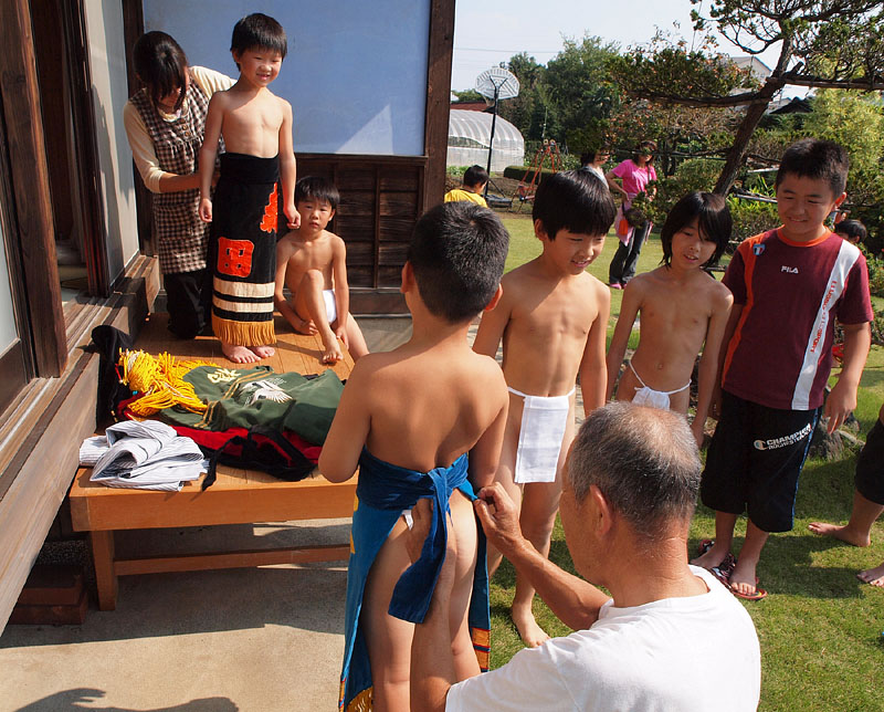 和やかな雰囲気でお爺さんやお母さんに自分の化粧廻しを締めて貰う子供たち